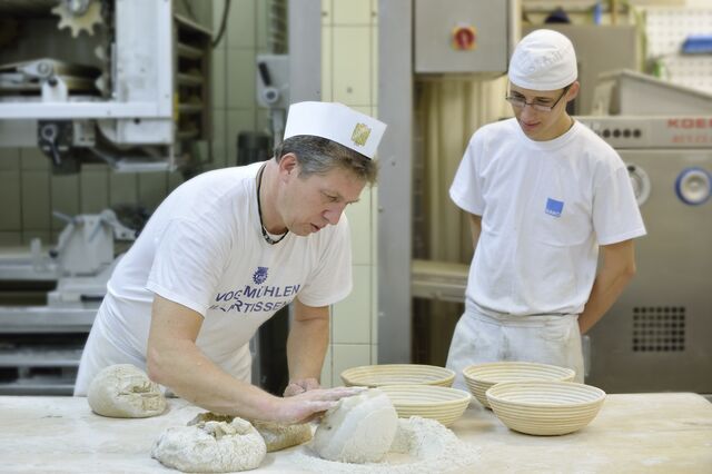 In der Bäckerei schaut der Praktikant dem Bäcker über die Schulter